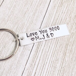 May include: Silver keychain with a rectangular tag that reads "Love You 3000 ♥ M.J & D".