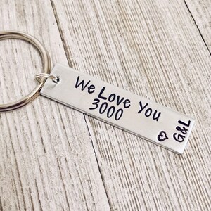 May include: Silver keychain with a rectangular tag that reads "We Love You 3000" with a heart and the initials "G&L" engraved on it.