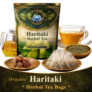 Op de afbeelding: Een assortiment Haritaki kruidenthee producten. Een zakje thee, een kopje thee, losse theebladeren, theezakjes en hele gedroogde vruchten worden getoond. De verpakking bevat de tekst "Origins Blue Lotus Haritaki Herbal Tea Bags".