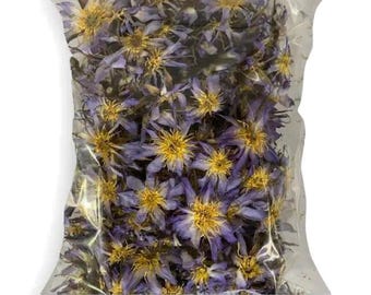 May include: A transparent plastic bag containing dried blue lotus flowers. The flowers have yellow centres and are labelled "True Nymphaea Caerulea" and "House Of Origins".