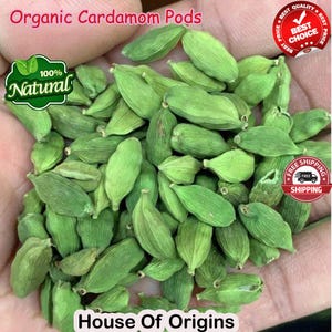 Op de afbeelding: Een close-up afbeelding van een hand die een stapel groene kardemompeulen vasthoudt. De peulen zijn in een willekeurig patroon gerangschikt en zijn allemaal van vergelijkbare grootte en vorm. De afbeelding is gelabeld met "Organic Cardamom Pods" en "100% Natural".