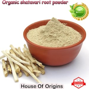 Peut inclure: Un bol de poudre de racine de shatavari de couleur brun clair, avec un tas de racines de shatavari séchées au premier plan. Le bol est en terre cuite et a un glaçage brun. Le texte "Organic shatavari root powder" est en haut de l'image, et le texte "House of Origins" est en bas de l'image. Un sceau doré avec le texte "100% NATURAL" est dans le coin supérieur droit de l'image.