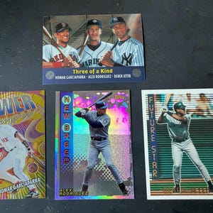 May include: A collection of baseball trading cards featuring players in action. The cards showcase Nomar Garciaparra, Alex Rodriguez, and Derek Jeter. Some cards have text like "POWER", "NEW BREED", and "FUTURE STAR".