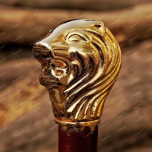 May include: A gold lion head finial with detailed carvings. The finial is mounted on a red wooden base.