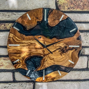 Könnte beinhalten: Eine runde Wanduhr aus Holz mit einer schwarzen und blauen Harzeinlage. Das Zifferblatt der Uhr hat weiße römische Ziffern als Stundenmarkierungen und schwarze Zeiger.