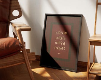 May include: A framed print with Arabic calligraphy in a black frame, leaning against a wall. The print features a maroon background with a green border and text in white. A wooden chair and side table are in the background.