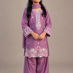 Young girl wearing a mauve purple embroidered salwar kameez with floral detailing, matching salwar pants, and dupatta, perfect for Eid, weddings, and traditional South Asian celebrations.