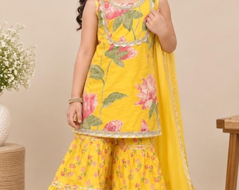 May include: A bright yellow sleeveless tunic featuring a large pink and green floral print, paired with matching wide-leg flared pants with a small floral pattern. The outfit includes a sheer yellow dupatta with silver trim detailing.