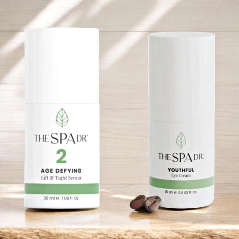 Peut inclure: Deux flacons cylindriques blancs de produits de soin de la peau avec des accents verts. L'un indique "THE SPA DR 2 AGE DEFYING Lift & Tight Serum 30 ml e 1 US fl. Oz." L'autre dit "THE SPA DR YOUTHFUL Eye Cream 15 ml e 0.5 US fl. Oz."