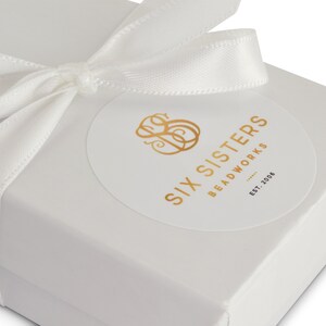 Pu&ograve; includere: Scatola regalo bianca con un nastro di raso bianco legato a fiocco. Un adesivo rotondo con lettere dorate recita "Six Sisters Beadworks Est. 2006".
