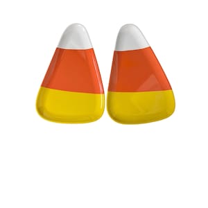 May include: Two candy corn pieces, a classic Halloween treat, are displayed against a white background. Each piece features a tri-color design: a white top, an orange middle, and a yellow base. The candies have a glossy, smooth appearance.