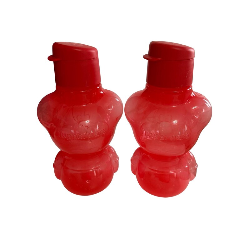 May include: Two translucent red plastic water bottles with a rounded, bear-like shape. Each bottle features a matching red flip-top cap and the embossed Tupperware logo on the front. The bottles have a wide midsection and a smaller base.