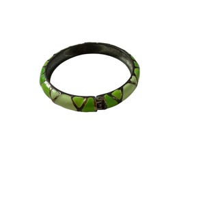 May include: A hinged bangle bracelet featuring a geometric pattern of alternating light green and bright lime green enamel segments separated by thin dark metal lines. The bracelet has a secure metal clasp mechanism visible on the side.
