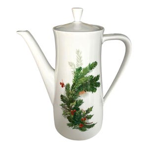 May include: White ceramic coffee pot with a lid and handle. The pot is decorated with a green and red Christmas tree design. The spout is long and slender, and the handle is curved.