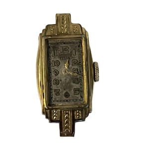 May include: Vintage gold-toned Elgin wristwatch with a rectangular face. The watch features a silver-colored dial with black numerals and hands. The watch case has an Art Deco design with decorative elements.