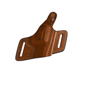 Puede incluir: Una funda de cuero marr&oacute;n con costuras visibles y dos ranuras para cintur&oacute;n. La funda est&aacute; dise&ntilde;ada para llevarse en la cadera y tiene un lazo para sujetarla al cintur&oacute;n. El cuero tiene un aspecto desgastado.