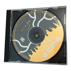 May include: A CD-ROM for "Streets of Sim City" in a clear plastic case. The disc features a cityscape design in yellow and gray, with the Maxis logo. The case is black with a spine.
