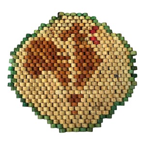 Könnte beinhalten: Ein rautenförmiger Untersetzer aus kleinen Holzperlen. Der Untersetzer hat ein Muster aus hellen und dunkelbraunen Perlen mit grünen Rändern. Einige rote Perlen sind im Design sichtbar. Dieser dekorative Artikel ist für die Küche geeignet.