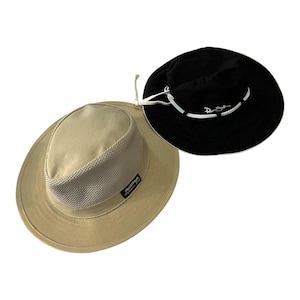 Puede incluir: Dos sombreros: un sombrero beige con una corona de malla y un sombrero negro con una banda blanca. El sombrero beige tiene un ala ancha y una pequeña etiqueta. El sombrero negro tiene texto blanco y un cordón.