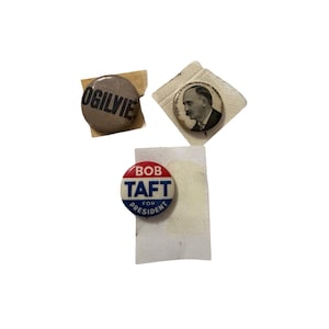 May include: Three circular political pinback buttons. One is grey with the black text OGILVIE. Another is white with a black and white portrait and the text FOR GOVERNOR GEO. W. NASH. The third is red, white, and blue with the text BOB TAFT FOR PRESIDENT.