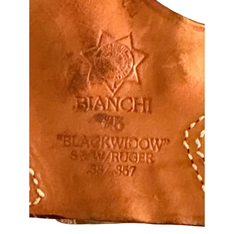 Puede incluir: Primer plano de una funda de cuero marr&oacute;n con el texto en relieve "BIANCHI" y "BLACKWIDOW" junto con "S&W/RUGER .38/.357". La funda presenta un dise&ntilde;o decorativo de estrella y costuras blancas.