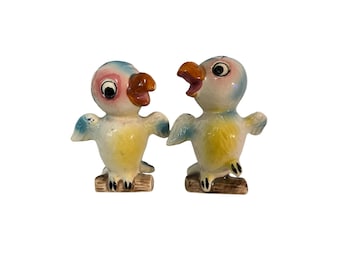 Par de figuras vintage de pájaros de cerámica japonesa en tonos pastel azul y amarillo, estilo kitsch de mediados de siglo.