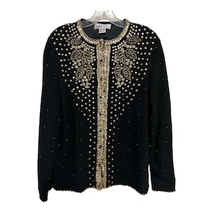 May include: Black cardigan with gold sequin and bead detailing. The sweater has a round neckline and a button-up front. The design includes a decorative pattern of sequins and beads around the neckline and down the front.