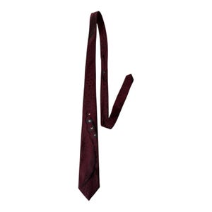 Könnte beinhalten: Eine bordeauxfarbene Krawatte mit gemustertem Design und dekorativen Verzierungen. Die Krawatte hat drei kreisförmige Akzente und einen strukturierten Stoff. Ein klassisches Accessoire für formelle oder geschäftliche Kleidung.
