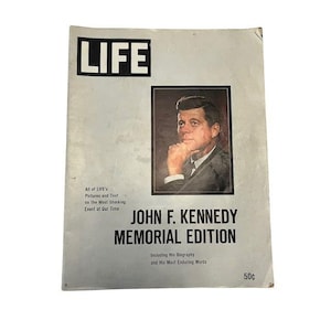 Pode incluir: Uma capa de revista LIFE vintage com um retrato de John F. Kennedy. A capa é uma edição comemorativa com o texto "JOHN F. KENNEDY MEMORIAL EDITION". A revista está envelhecida e desgastada.