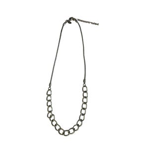 May include: A gunmetal-colored necklace with a chain of oval links. The necklace has a delicate chain that connects to the oval link chain. The necklace is on a white background.