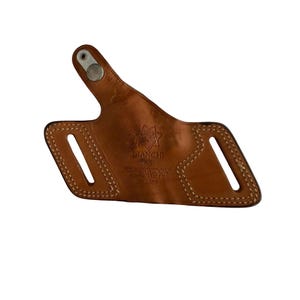 Puede incluir: Una funda de cuero marr&oacute;n con costuras blancas y un broche met&aacute;lico. La funda tiene dos ranuras y el texto "BIANCHI PROS BLACKWIDOW S&W RUGER 33-557". La funda est&aacute; dise&ntilde;ada para sujetar un arma de fuego.
