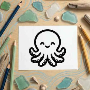 May include: A white card features a black line drawing of a smiling octopus. The image is surrounded by pencils, sea glass, and seashells on a light wood surface. The octopus has a round head and eight tentacles.