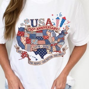 May include: White t-shirt featuring a patriotic design celebrating the USA's 250th anniversary. The graphic includes a map of the United States with a patchwork pattern in red, white, and blue, along with the text "USA 250th Anniversary 1776-2026".