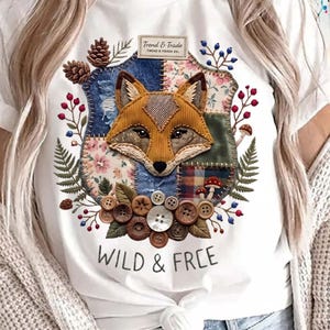 May include: White t-shirt with a fox design on a patchwork shield, floral, and button accents. The text "WILD & FREE" is printed below the design. The shirt also has the text "Trend & Trade Co."
