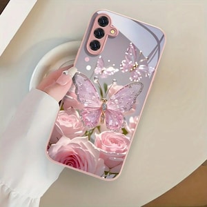May include: A rectangular smartphone case with a light pink border and a glossy back panel. The design features a large, detailed pink butterfly with glittery accents, smaller butterflies, and several soft pink rose blossoms against a light background.