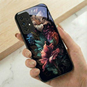 May include: A black smartphone case featuring a vibrant floral design. The case showcases a detailed illustration of various flowers in shades of pink, red, blue, and white, set against a dark background. The phone's camera and buttons are visible.