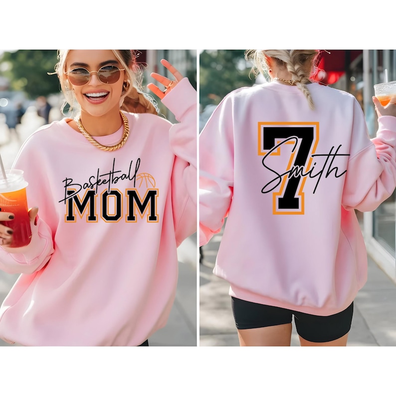 May include: A light pink sweatshirt with the words "Basketball MOM" in black script and block letters, with a basketball graphic. The back of the sweatshirt has the number 7 and the name "Smith" in black and yellow.