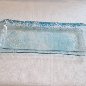 Puede incluir: Una bandeja rectangular de servir de vidrio azul claro con una superficie texturizada y un diseño moteado.