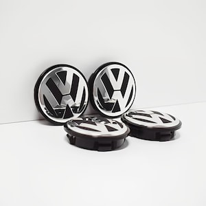Op de afbeelding: Vier zwarte en zilveren wieldoppen met het Volkswagen-logo.