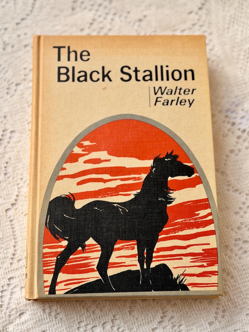 Peut inclure: Un livre de poche vintage intitul&eacute; "The Black Stallion" de Walter Farley. La couverture pr&eacute;sente une silhouette noire de cheval sur un fond rouge et cr&egrave;me. Le livre a une tranche de couleur cr&egrave;me.