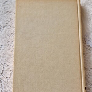 Peut inclure: Un livre &agrave; couverture rigide avec une couverture et un dos beiges. La couverture a un aspect textur&eacute;. Le livre est rectangulaire et semble ferm&eacute;. Le dos est d'une teinte beige plus claire.