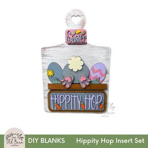 May include: A wooden Easter-themed DIY blank with a heart-shaped cutout. The design features a bunny's backside, Easter eggs, and the words "Easter" and "Hippity Hop." The color palette includes white, gray, pink, and orange.