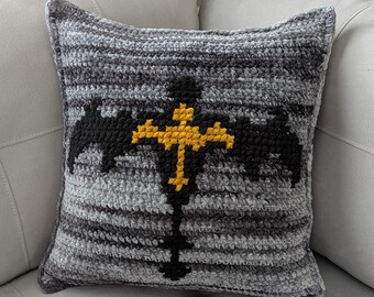 May include: A gray and black crocheted pillow with a yellow and black dragon design.