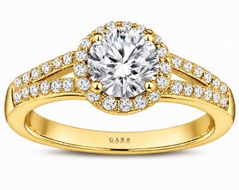 Könnte beinhalten: Ein Ring aus Gelbgold mit einem großen runden Brillantschliff-Mittelstein, der von einem Kranz kleinerer runder Steine umgeben ist. Die geteilte Ringschiene ist mit Pavé-gefassten Steinen besetzt. Innen ist der Ring mit GAR JEWELRY graviert.