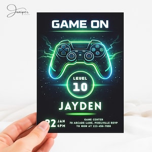 Op de afbeelding: Een zwarte uitnodigingskaart met neon groene en blauwe accenten. De kaart heeft een gloeiende game controller afbeelding met de woorden "GAME ON" bovenaan en "LEVEL 10" in een cirkel. De naam "JAYDEN" staat onder de cirkel, met evenementdetails onderaan.