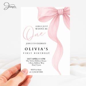 Pode incluir: Um cartão de convite branco com um grande laço e fita rosa em aquarela. O texto diz "GIRLS JUST WANNA BE One" e "OLIVIA'S FIRST BIRTHDAY". Inclui detalhes do evento: data, hora, local e informações de RSVP.