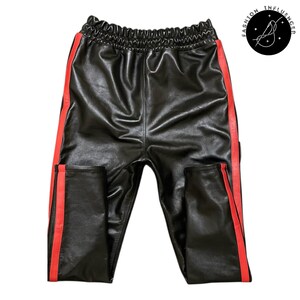 May include: Black leather pants with red side stripes and an elastic waistband. The pants have a shiny finish and a casual, sporty style. The Fashion Influencer logo is in the upper right corner.