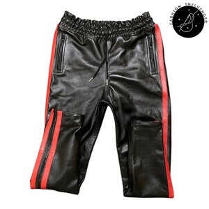 May include: Black leather pants with red side stripes. The pants have an elastic waistband with a drawstring, and two zippered pockets. The pants are made of a shiny, smooth material.