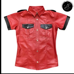 May include: Red leather short-sleeve shirt with black accents on the shoulders, pocket flaps, and sleeve cuffs. The shirt has two chest pockets and gold-colored buttons. The shirt is a button-down style.