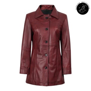 May include: A burgundy leather coat with a collared neckline and button-up closure. The coat features a tailored design with vertical seams and a knee-length hemline. The coat has long sleeves and a classic, timeless style.